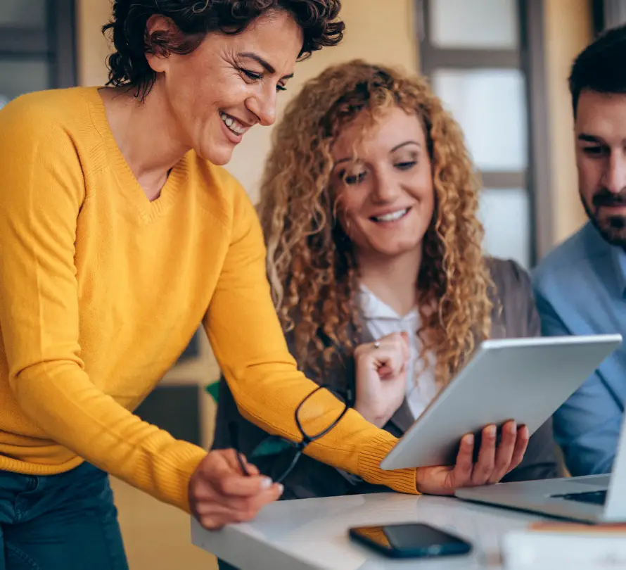 Three colleagues reviewing information on a tablet during a business meeting.